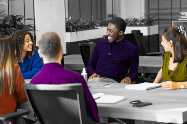 Schwarz-Weiß-Bild, nur Kleidung und Hautfarbe sind in Farbe. Eine Gruppe von fünf jungen Menschen arbeitet zusammen.