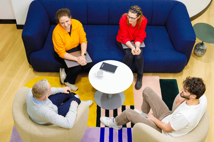 Eine Gruppe von vier leger gekleideten Kollegen saß plaudernd auf dem Sofa.