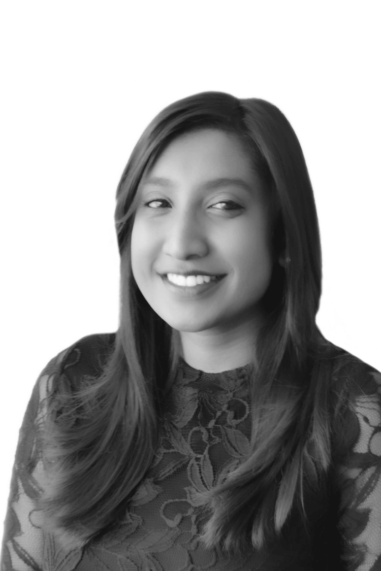 Ein Schwarz-Weiß-Bild einer jungen Frau mit langen Haaren, die in die Kamera lächelt. 