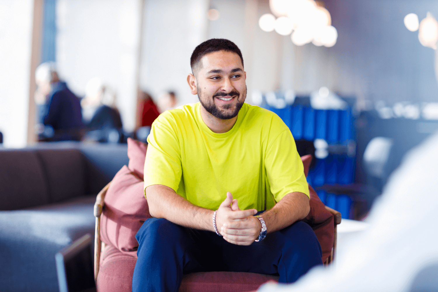 Un jeune homme vêtu d'un tee-shirt jaune est assis sur une chaise rouge.