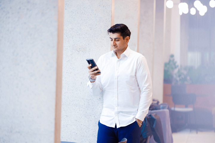 Un homme regarde son téléphone portable en s'appuyant sur un pilier.