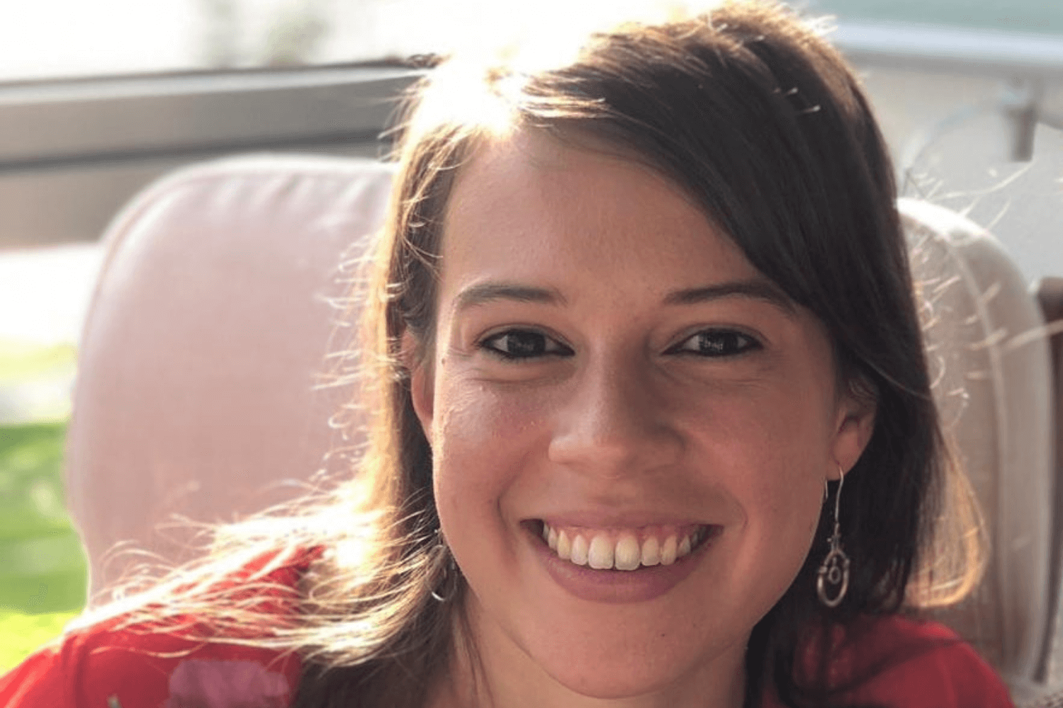 一位深色头发略长于肩的女性，身穿红色花纹上衣，对着镜头微笑。