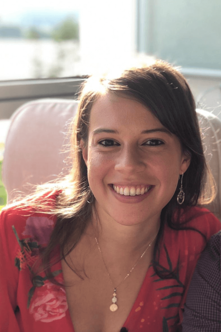 一位深色头发略长于肩的女性，身穿红色花纹上衣，对着镜头微笑。