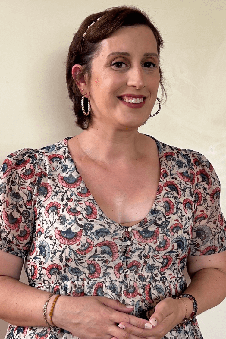 一位棕色短发、戴金箍耳环的女性。她身穿一件多色花纹上衣。