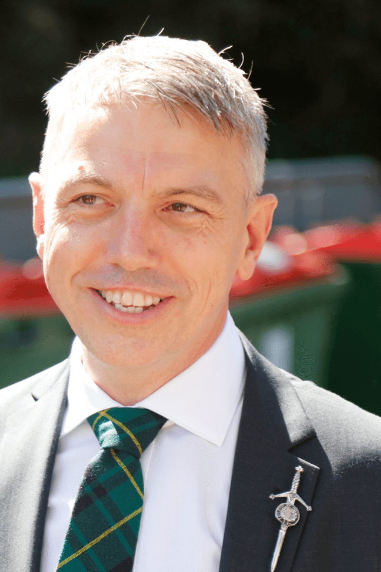 一个身穿白色短衣、黑色夹克、系着绿色领带的男人。